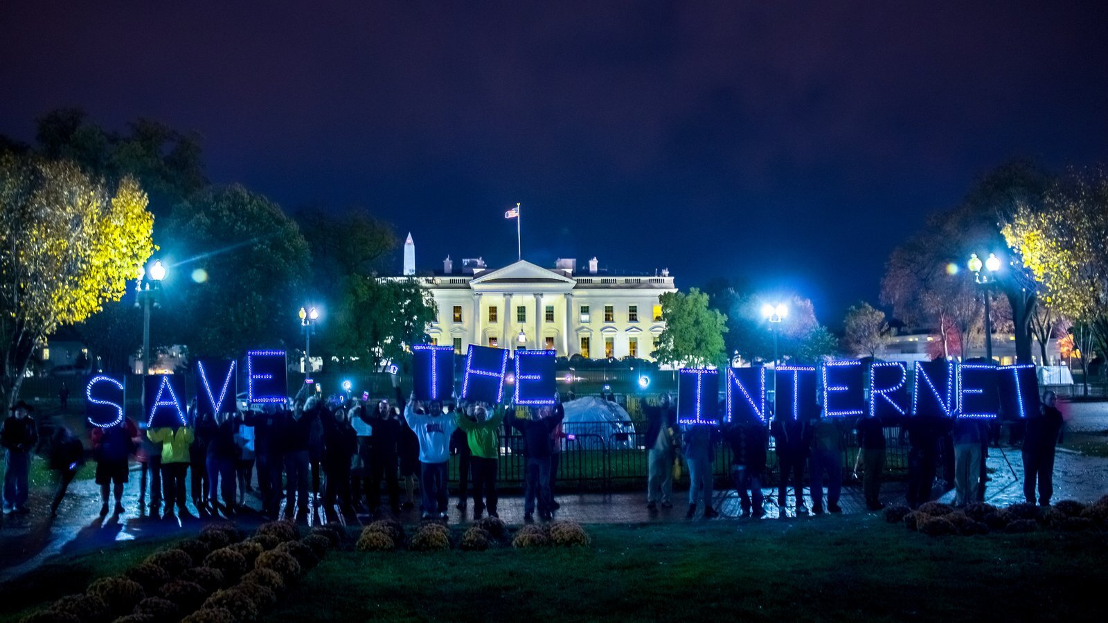 Activists spelling out “SAVE THE INTERNET” in illuminated letters in front of the White House at night